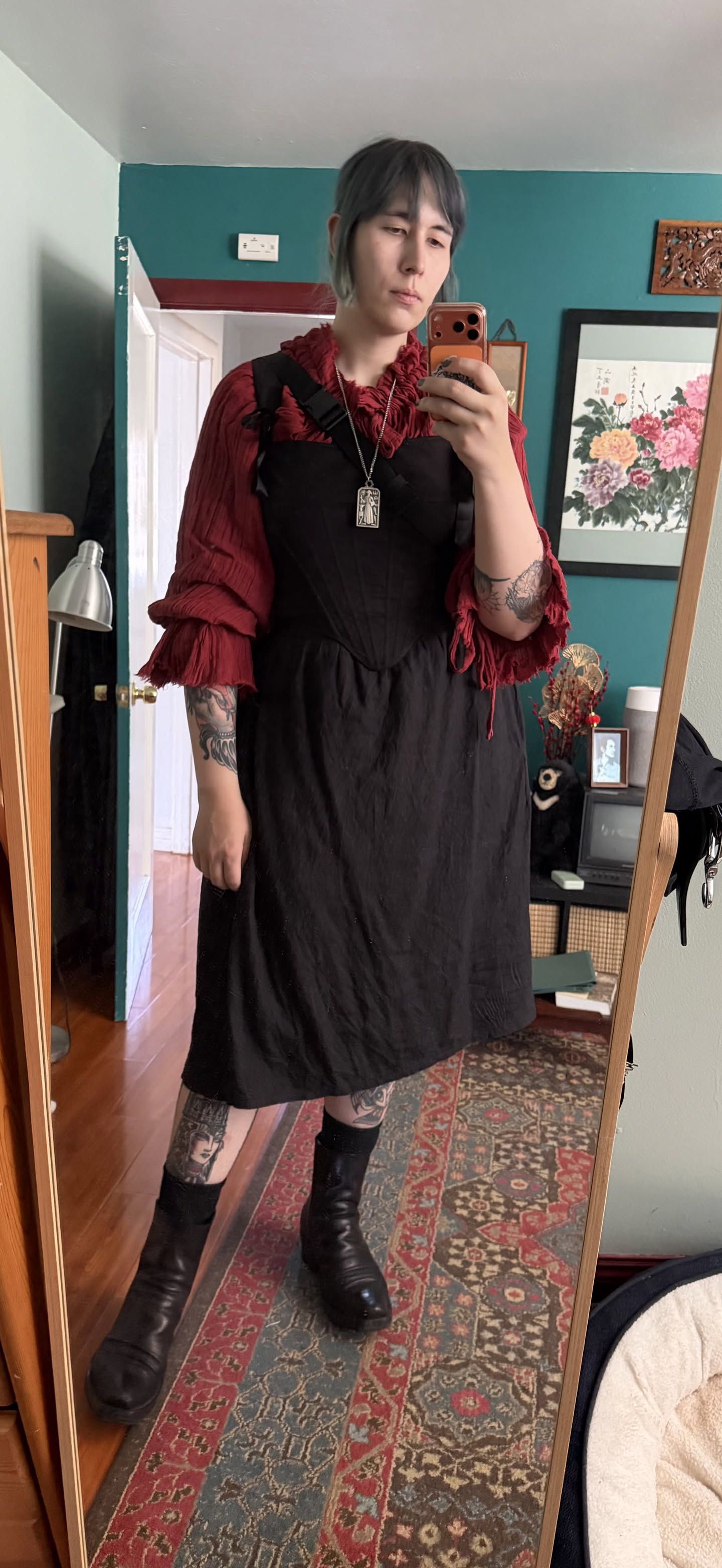 chastity wearing a red chemise, a pair of black stays, and a black linen midi skirt